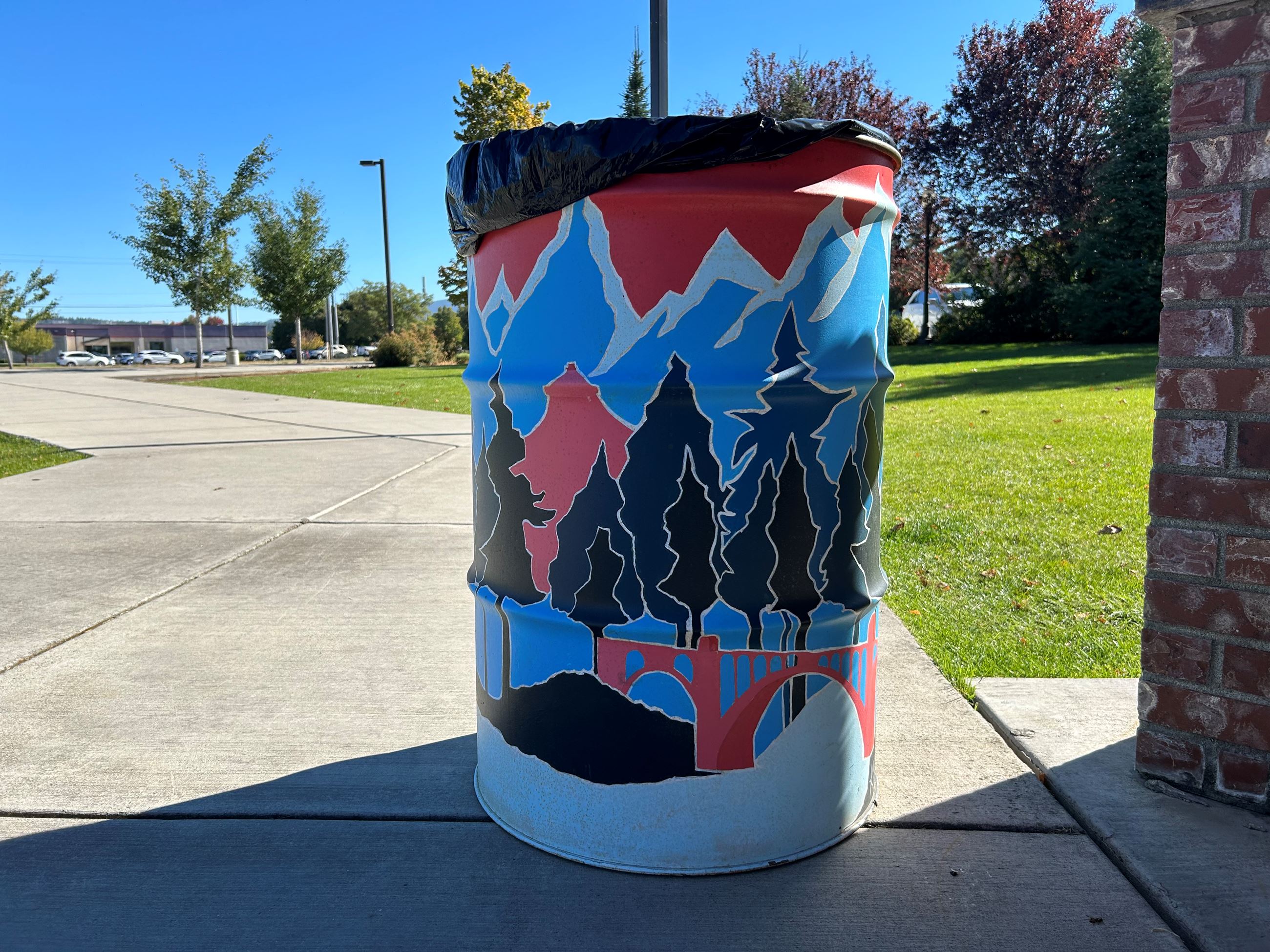 Image of 50 gal metal can with Spokane monument art painted on it.